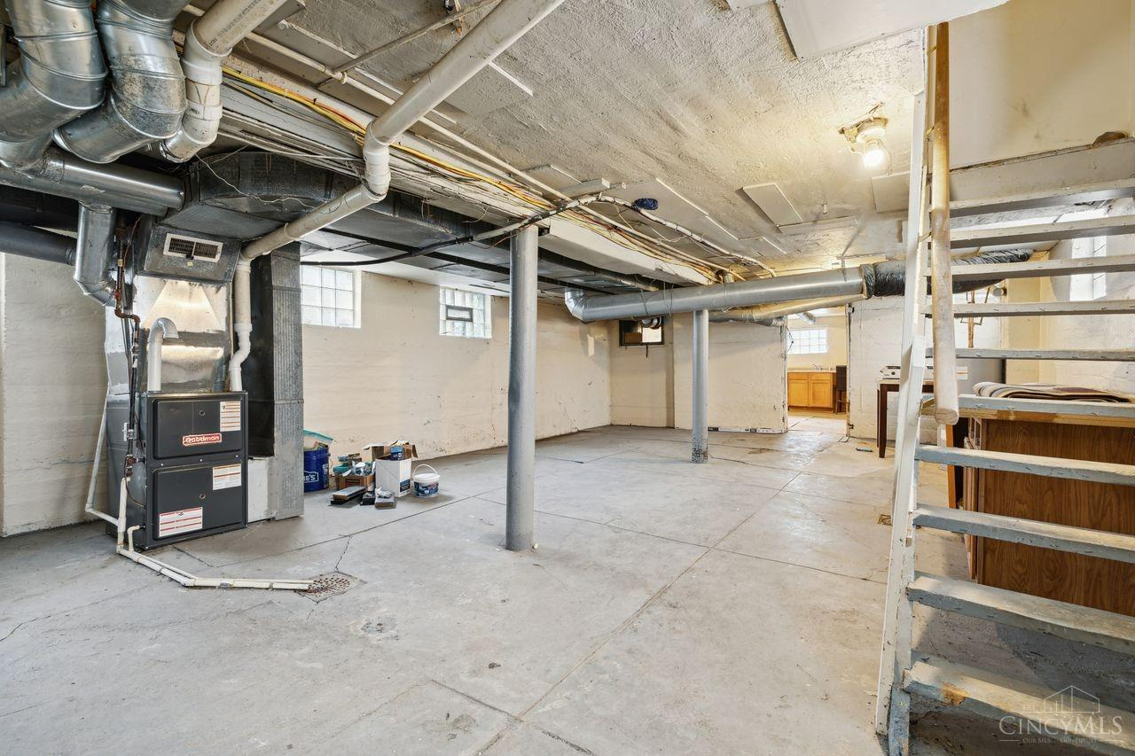 Unfinished basement with exposed ductwork, a furnace, and concrete floors.
