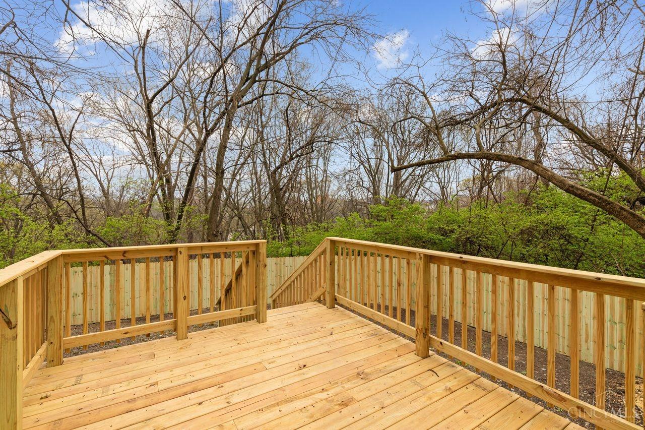 Wooden deck with stairs and railings overlooking a wooded yard.