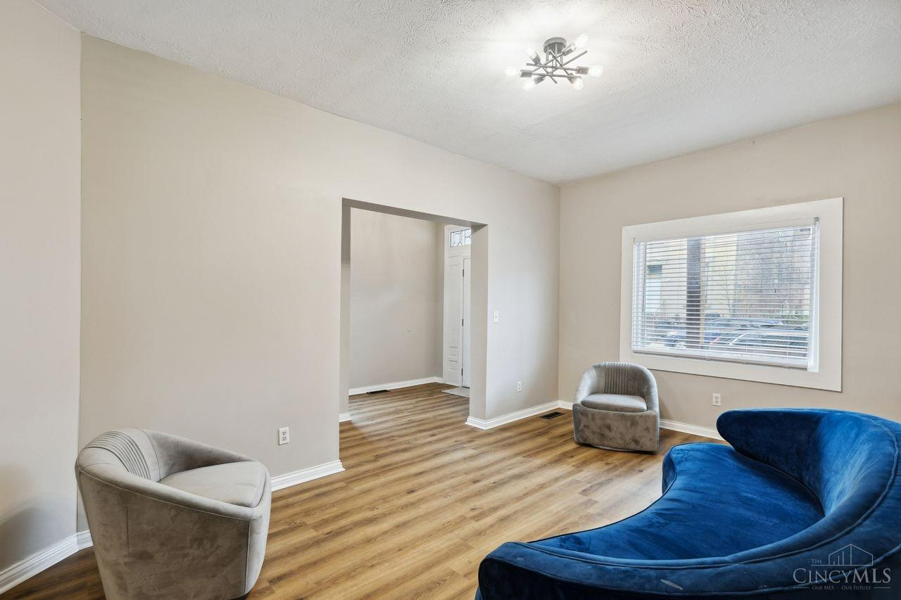 Living room with a curved blue sofa, gray armchairs, and wood-look flooring.