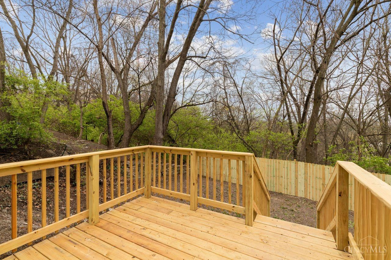 Wooden deck and steps overlooking a fenced, wooded backyard.