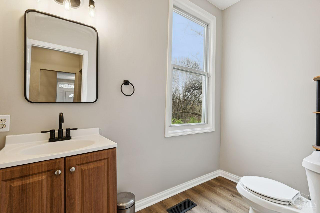 Bathroom with a wood vanity, black faucet, and window overlooking leafless trees.