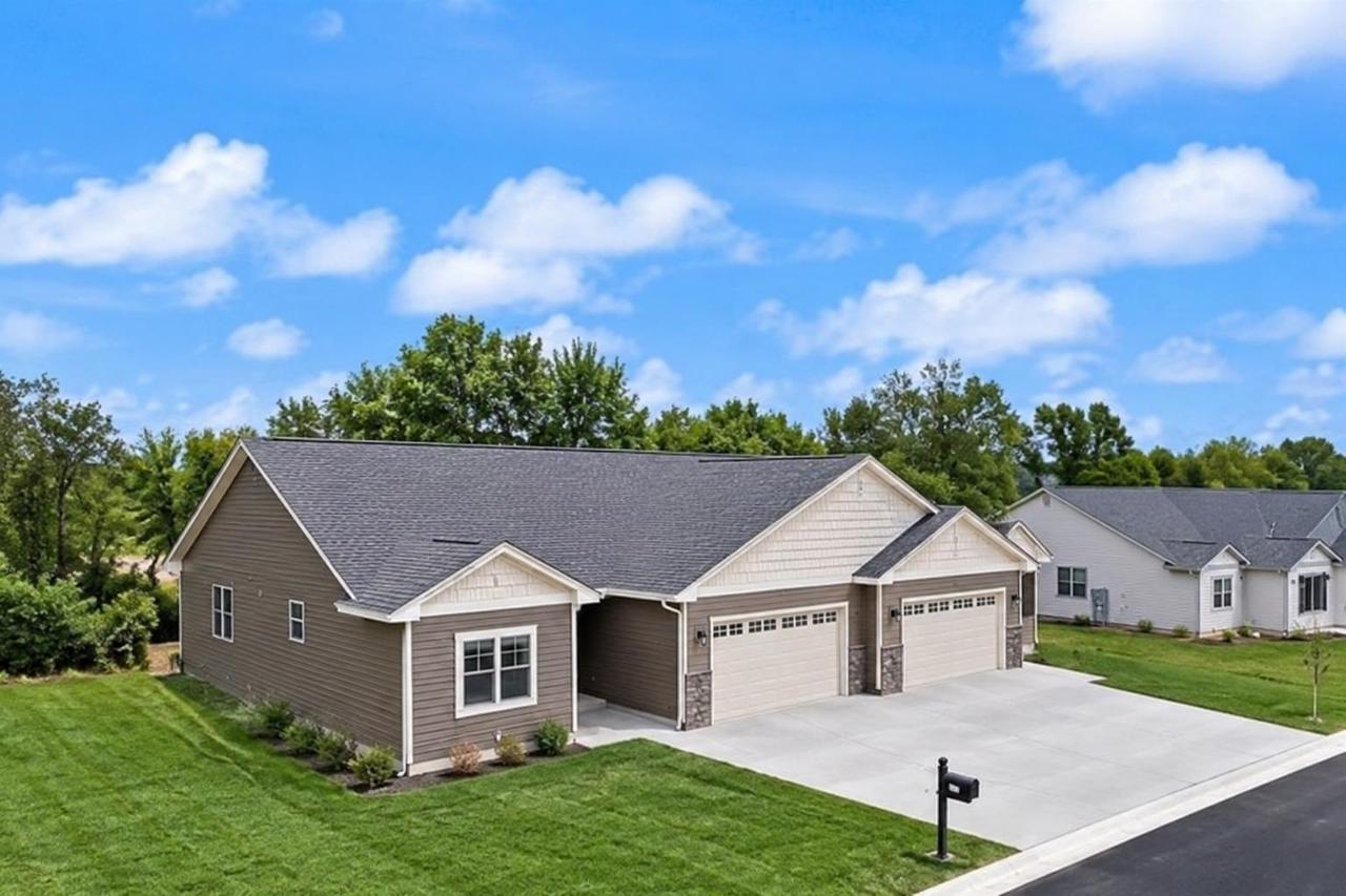 Tan single-story home with two garage doors and a wide driveway beside neighboring homes.