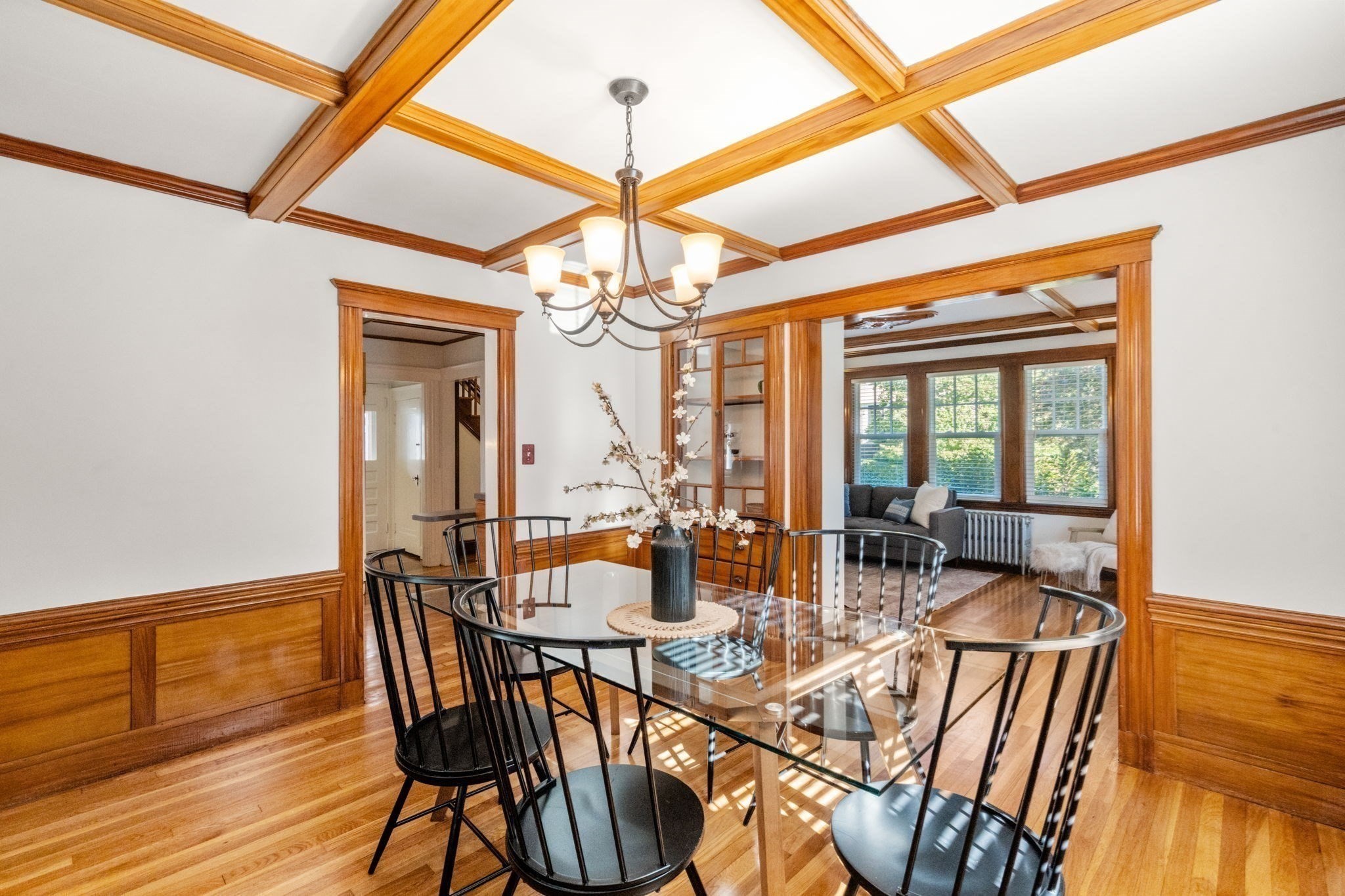 Dining room with a coffered wood ceiling, glass table, and adjoining sitting room.