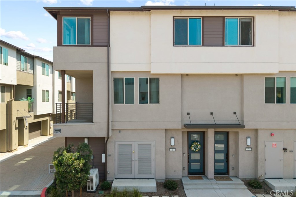 Modern two-story attached home with a small balcony and two front doors.