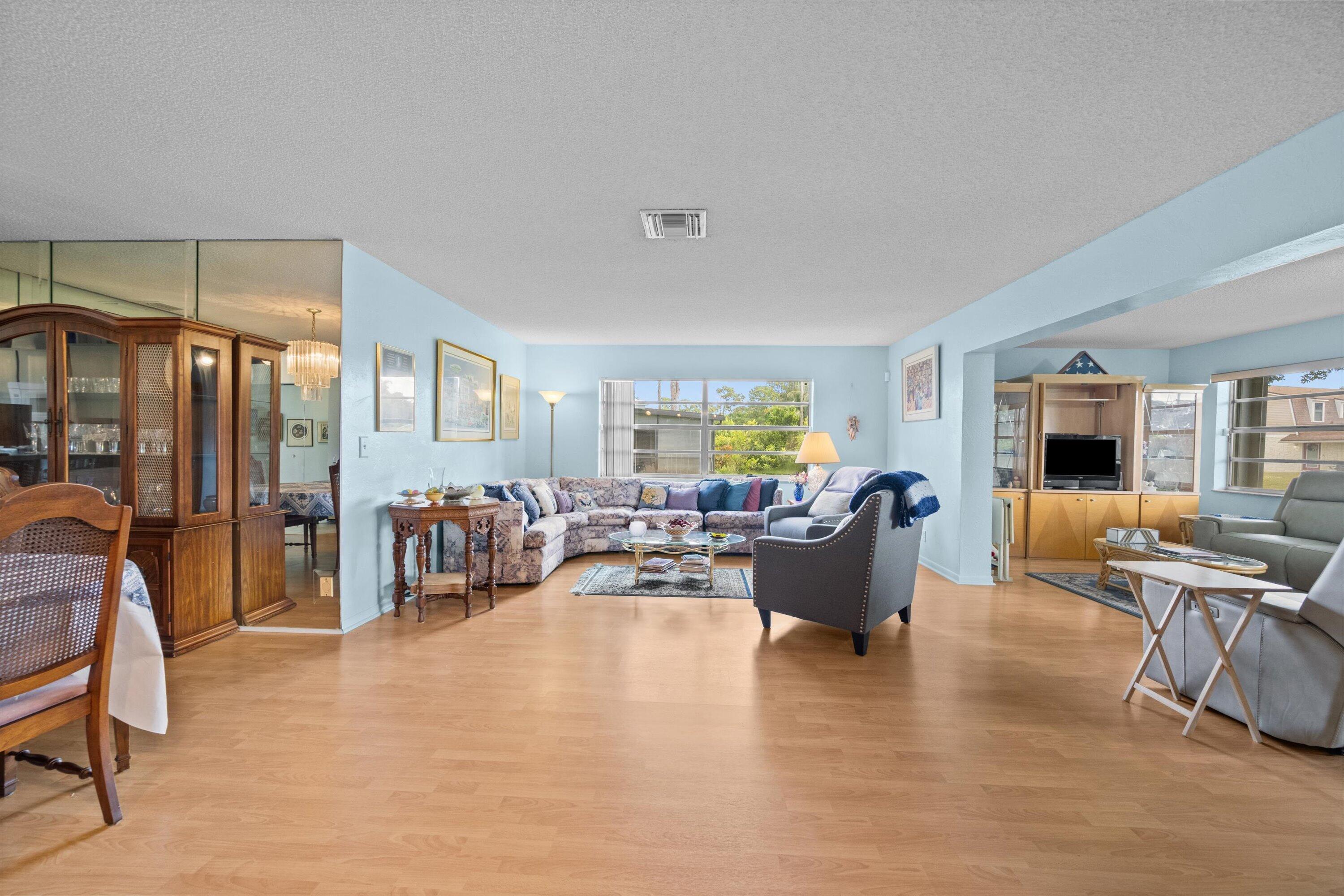 Furnished living room with a floral sectional, blue walls, wood floors, and large windows.