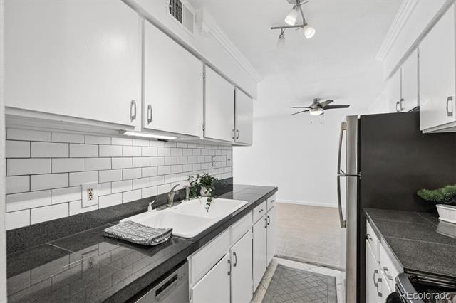 Kitchen with white cabinets, dark countertops, and a white subway tile backsplash.