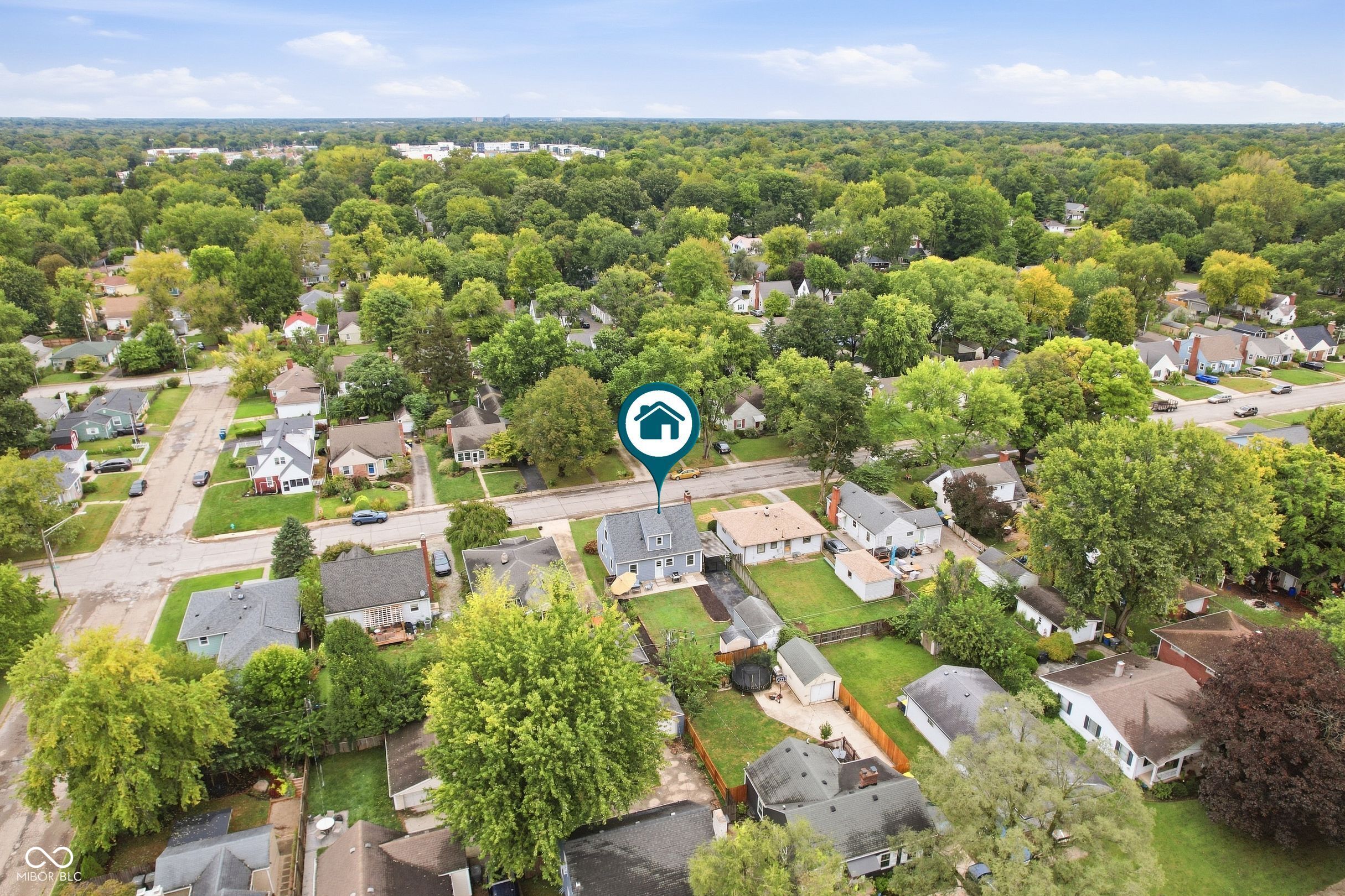 Aerial view of the blue house marked among tree-lined neighborhood streets.