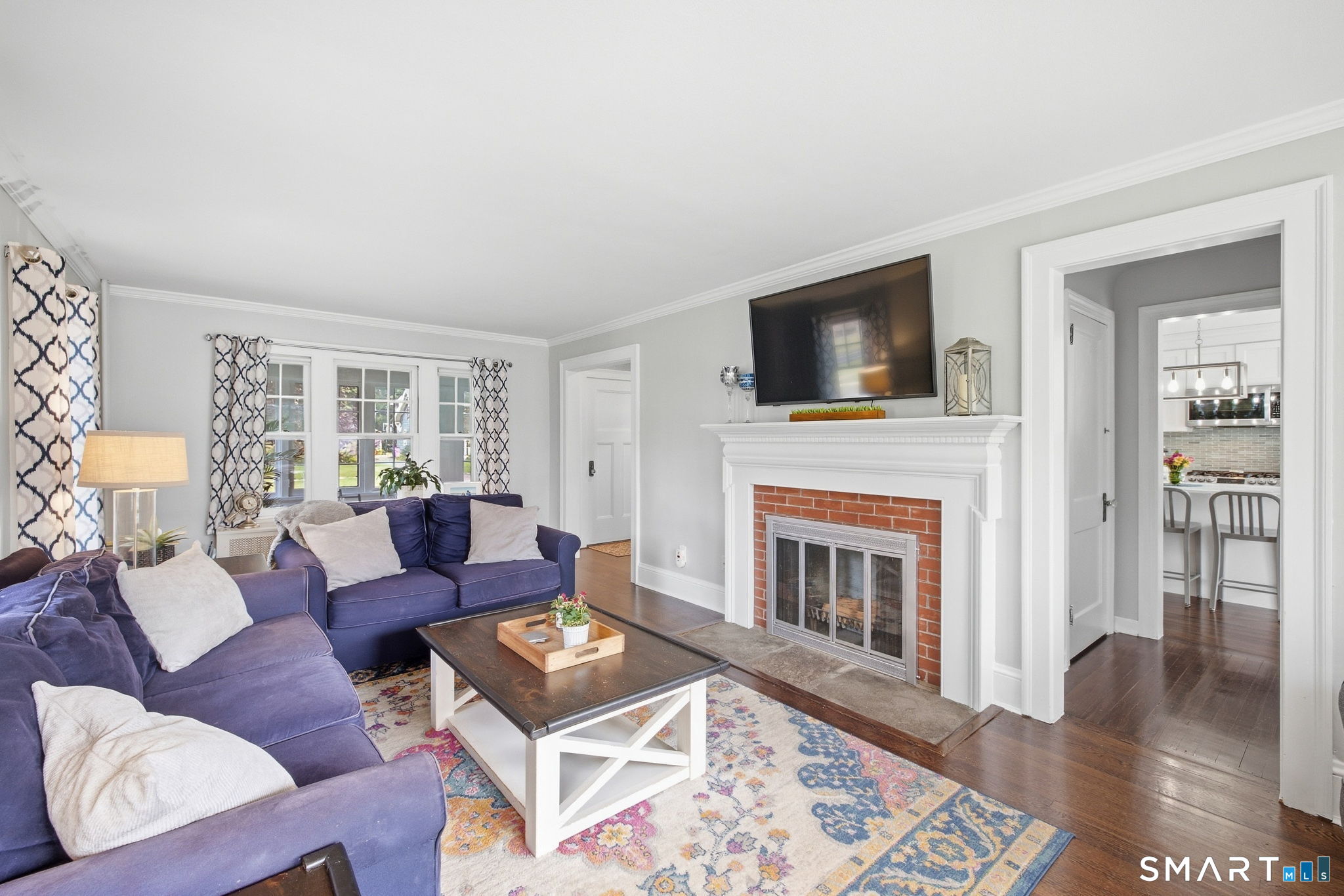 Living room with purple sectional sofas, a brick fireplace, and a doorway to the kitchen.