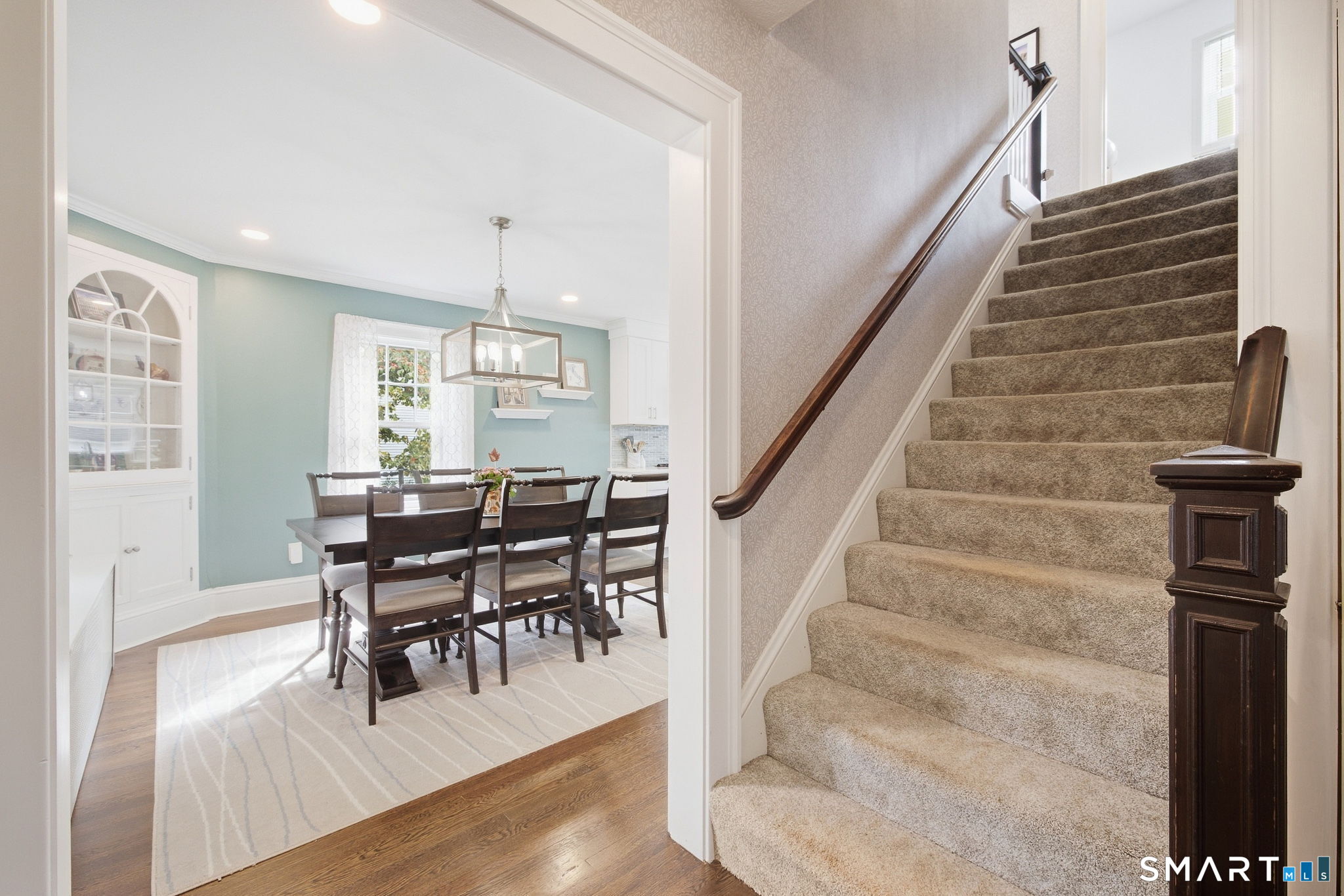 Dining room beside a carpeted staircase with a dark wood railing.