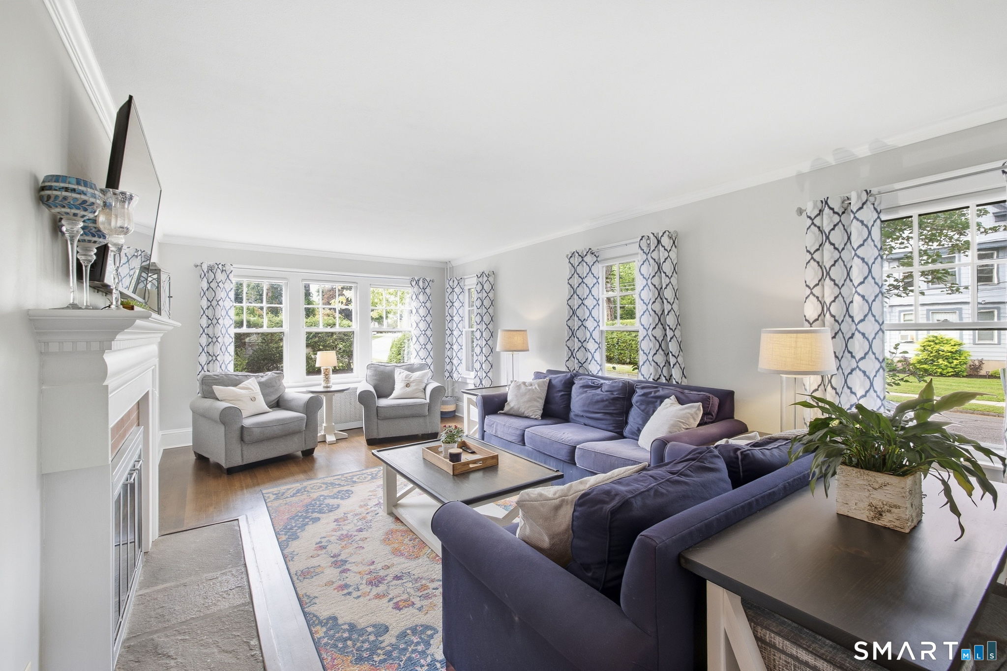 Living room with navy sofas, a white fireplace, and large windows.