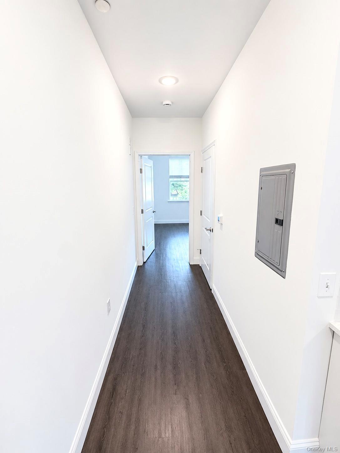 Unfurnished hallway with dark flooring, recessed lights, and an electrical panel.