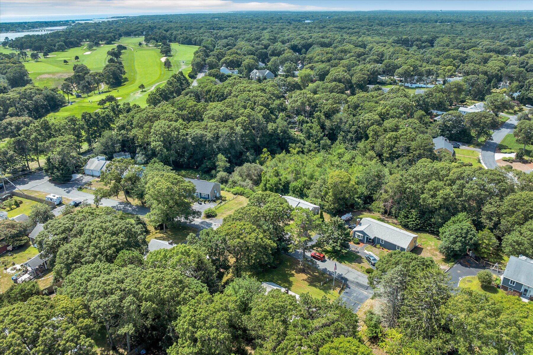 Aerial view of a wooded neighborhood beside a golf course.