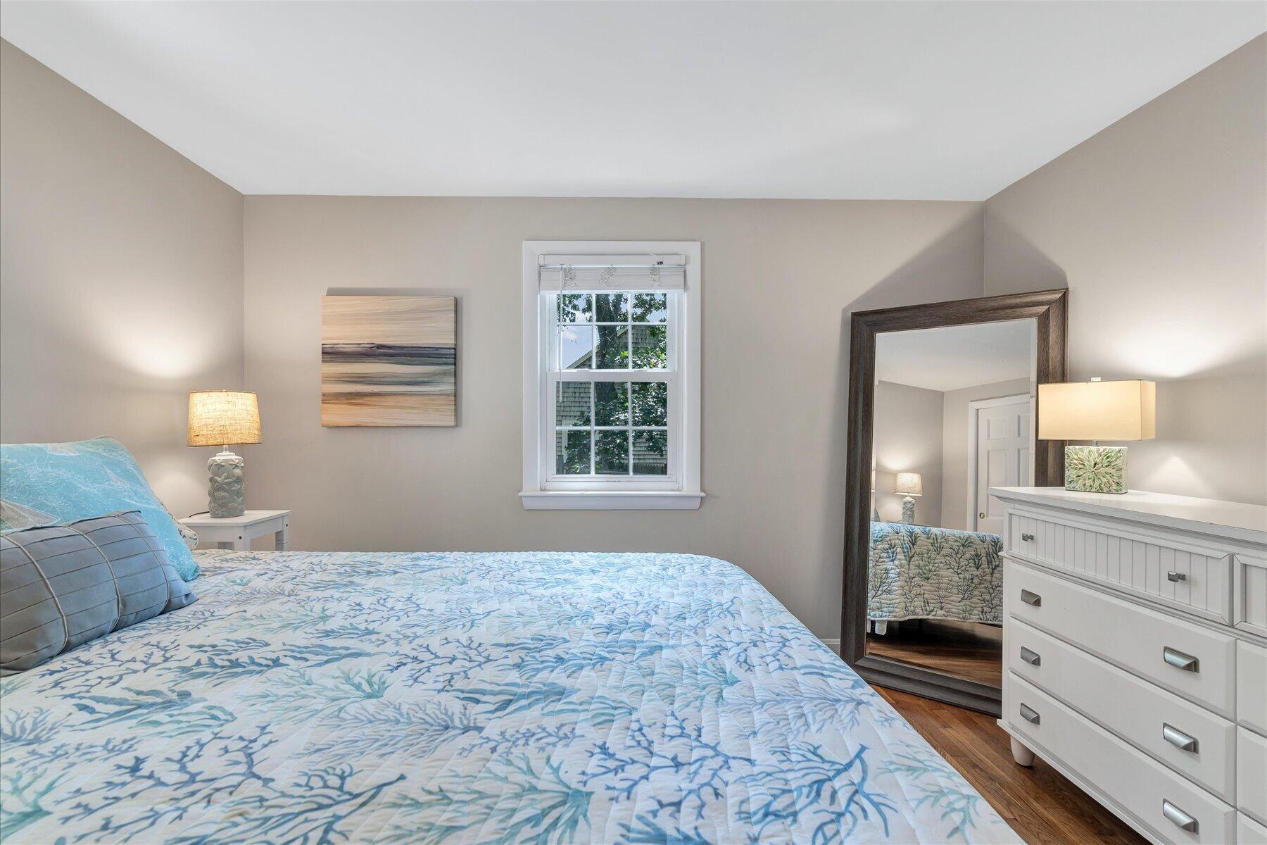 Bedroom with blue-and-white patterned bedding, a white dresser, and a large floor mirror.