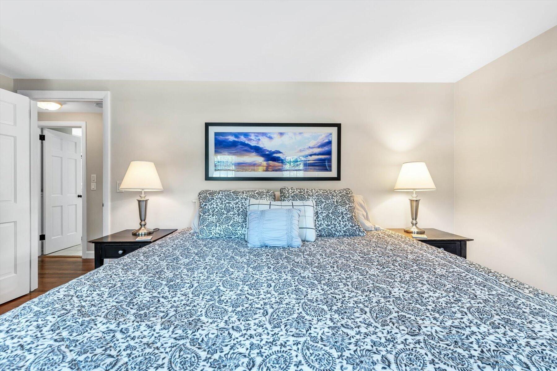 Bedroom with blue-and-white patterned bedding, matching bedside lamps, and framed wall art.