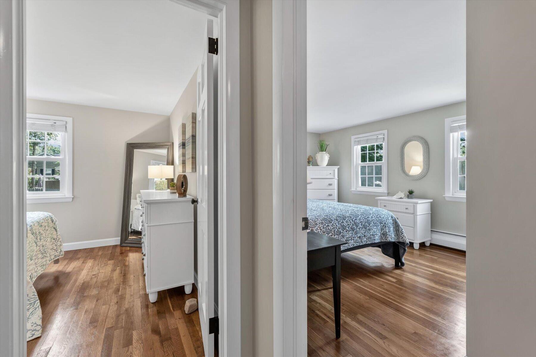 Two furnished bedrooms with hardwood floors, viewed through open doorways.