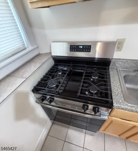 Kitchen gas range with four burners beside a sink and speckled countertop.