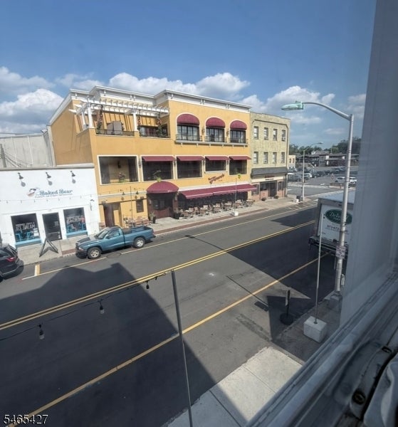 Downtown street view with a yellow commercial building, burgundy awnings, and outdoor seating.