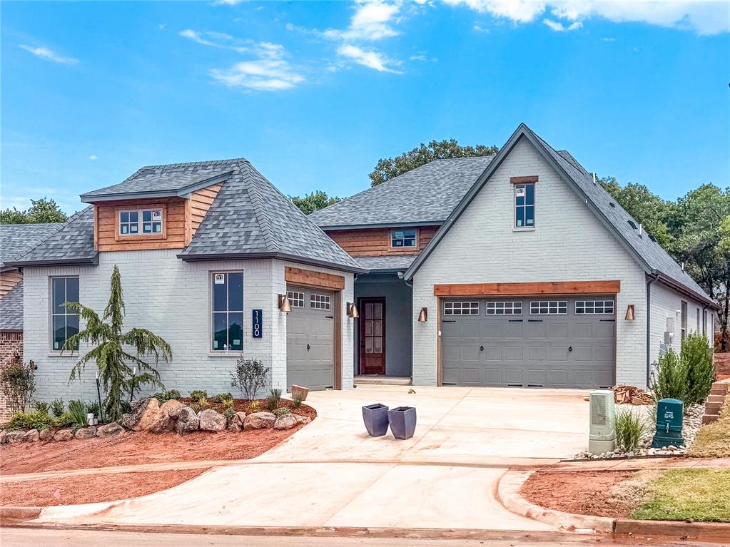 White brick home with attached garages, wood accents, and a broad concrete driveway.