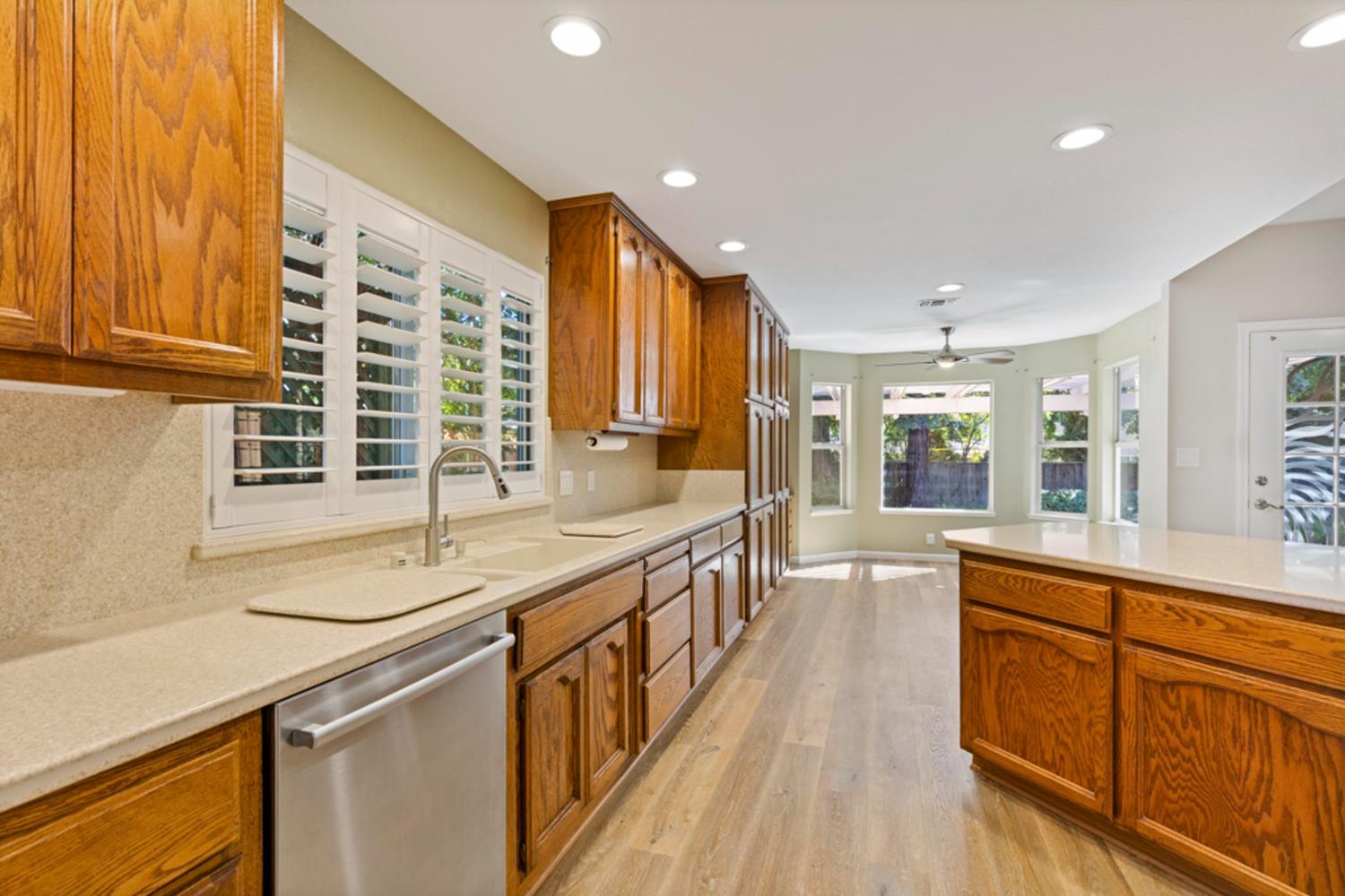 Bright kitchen with warm wood cabinetry, a central island, and plantation-shuttered windows.