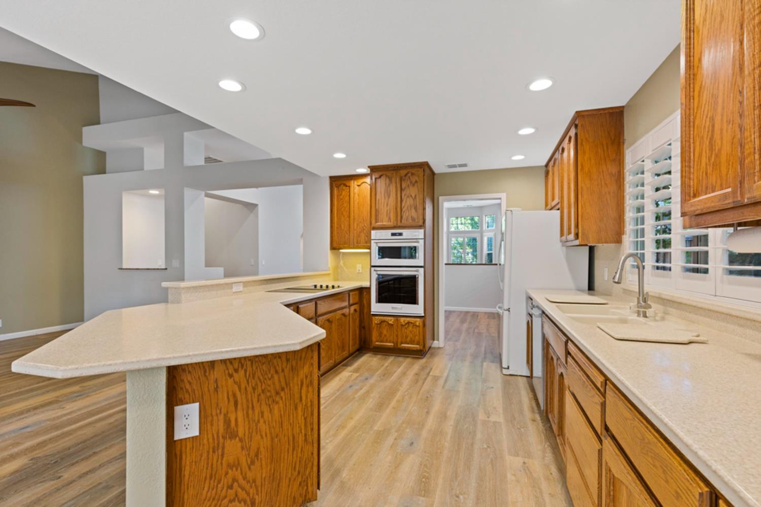 Kitchen with wood cabinets, a large peninsula, and double wall ovens.