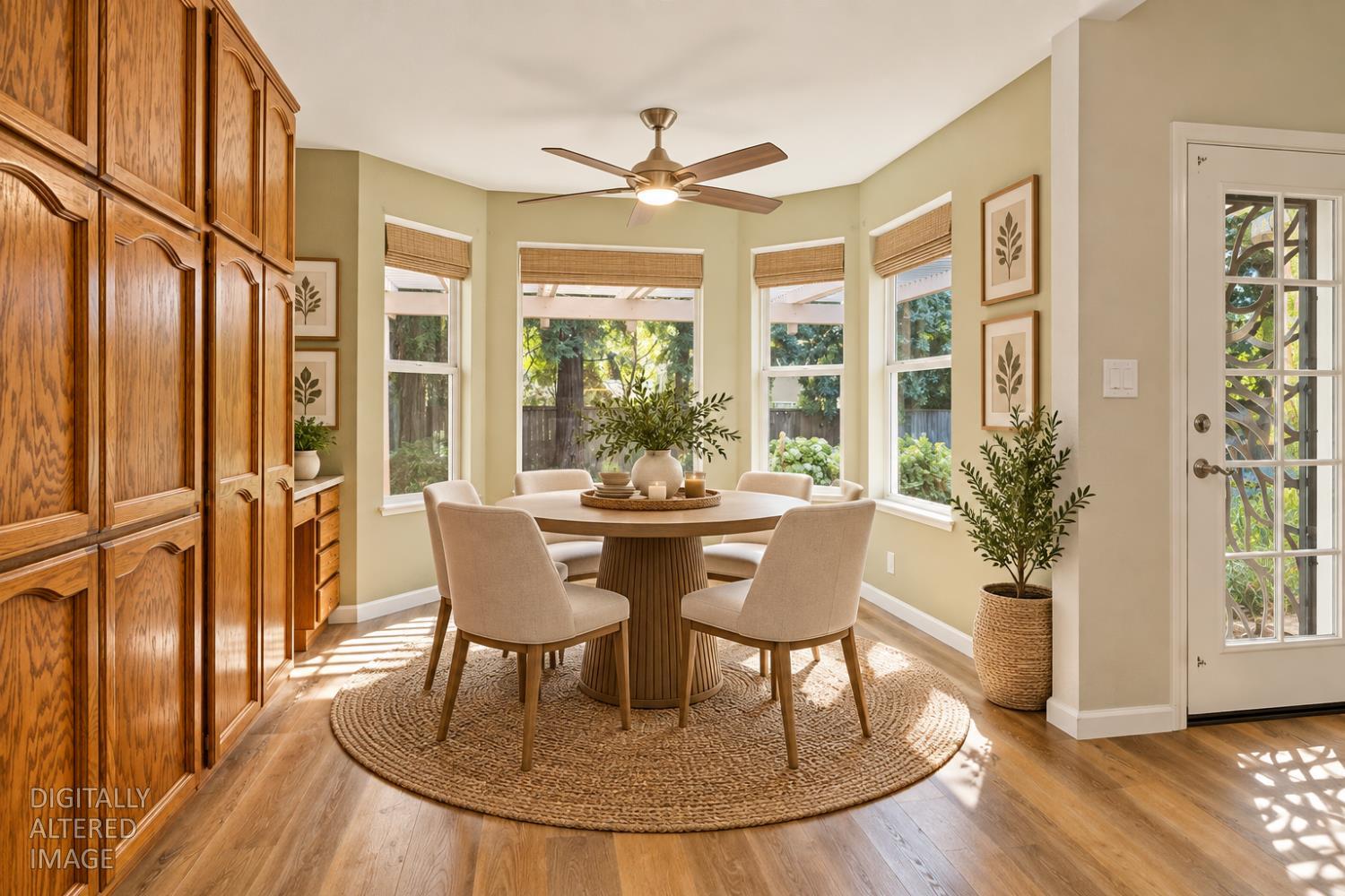 Dining nook with round table, built-in wood cabinets, and windows overlooking a leafy yard.