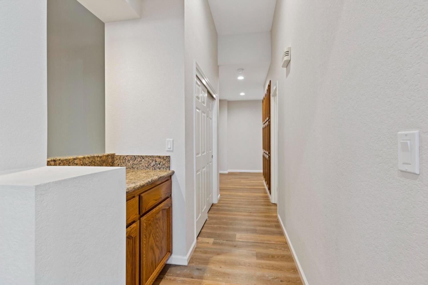 Hallway with wood-look flooring and a granite-topped wooden cabinet.