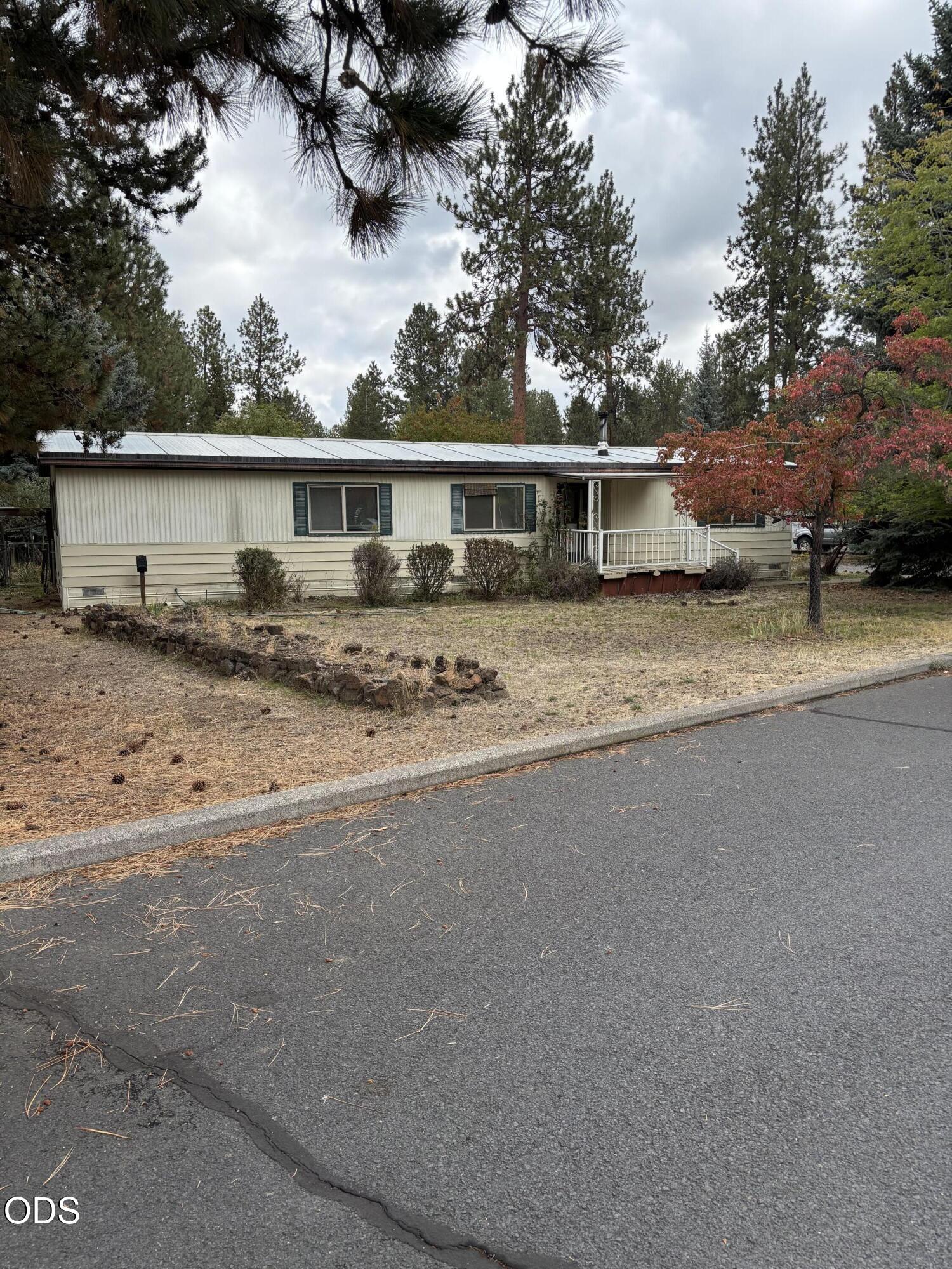 Single-story office building among pine trees, with a small entrance deck and red autumn foliage.