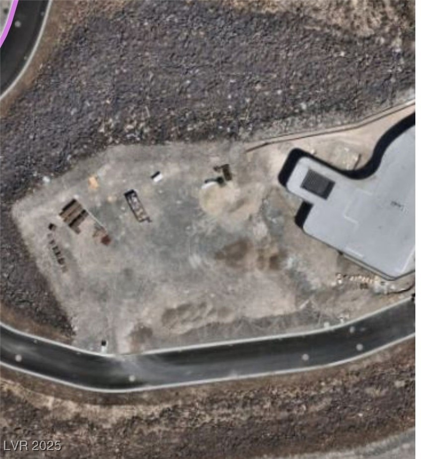 Aerial view of a building on a cleared desert lot beside a curved road.