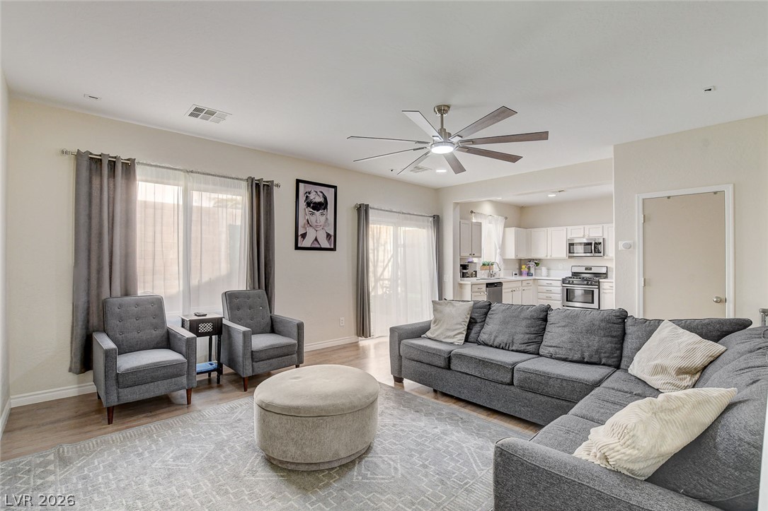 Living room with a gray sectional, armchairs, and an open kitchen behind it.