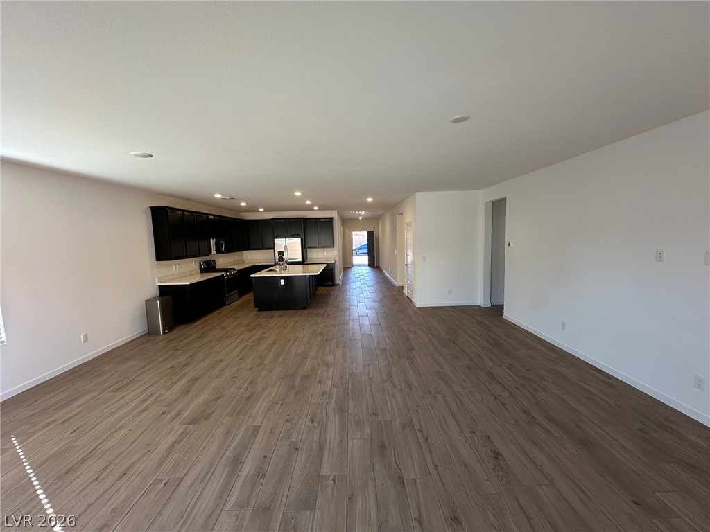 Open-plan living area with wood-look flooring and a black-cabinet kitchen with central island.