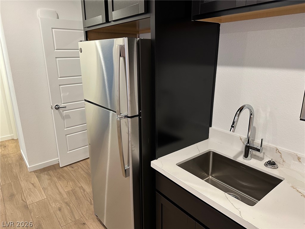 Kitchen with a stainless refrigerator, deep sink, dark cabinets, and white veined countertops.