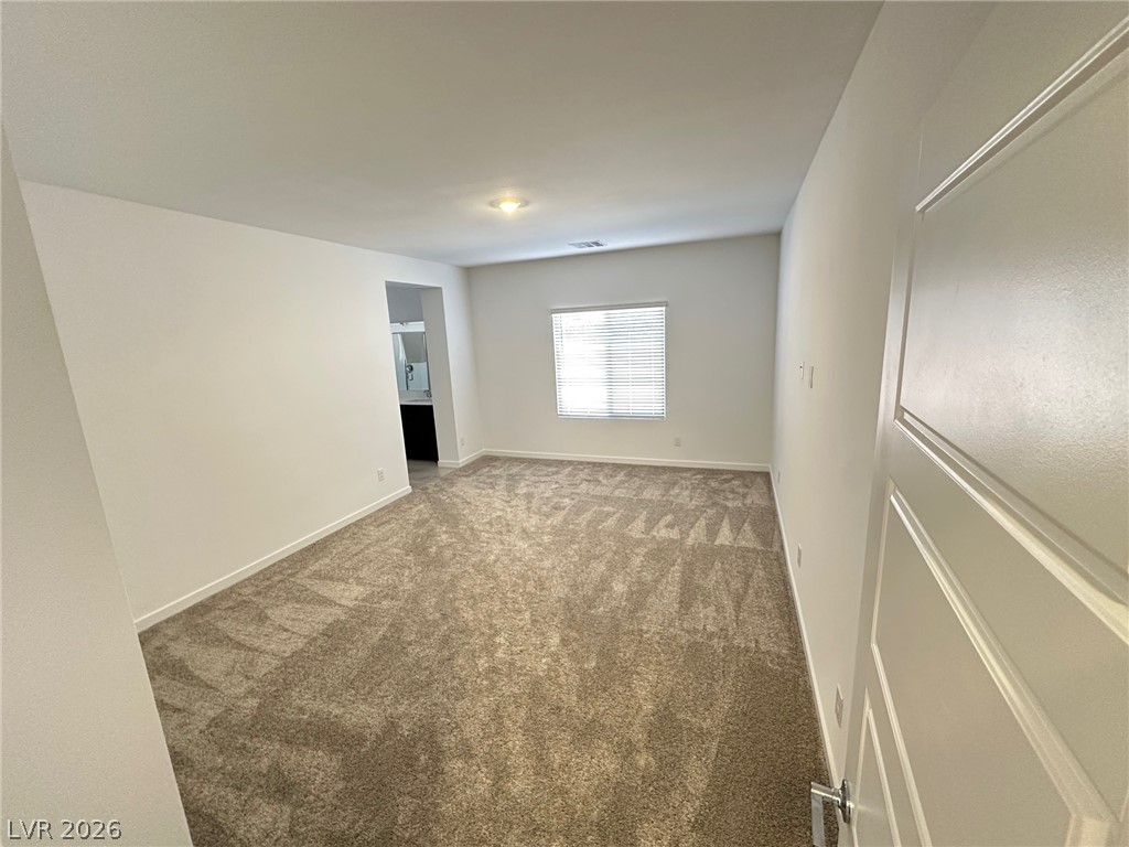 Empty carpeted room with a window and an open doorway.