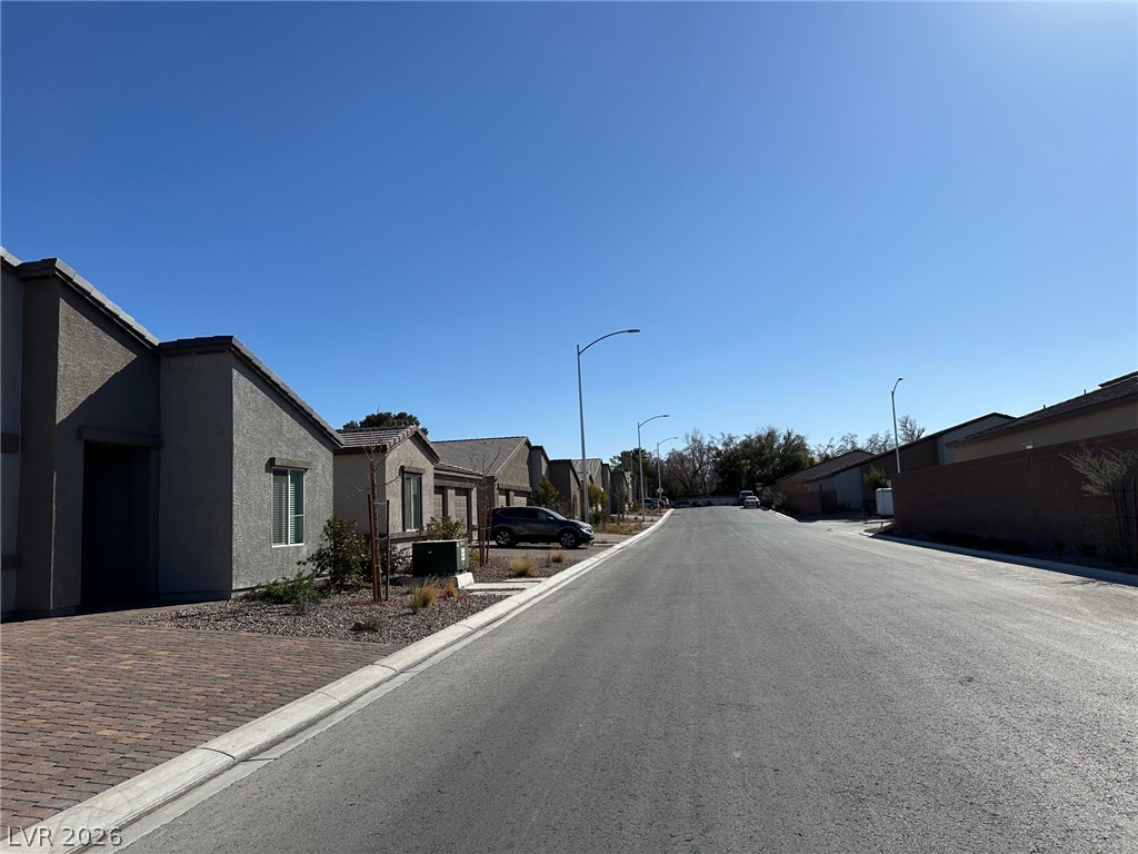 Residential street with single-story homes and desert landscaping under a clear blue sky.