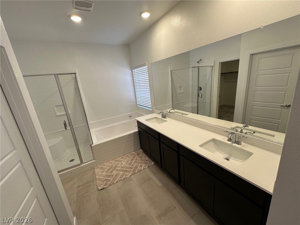 Bathroom with a dark double vanity, large mirror, built-in tub, and glass-enclosed shower.