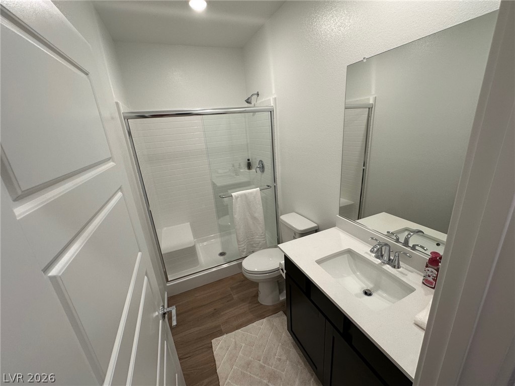 Bathroom with a glass-enclosed white-tile shower and dark vanity with a large mirror.