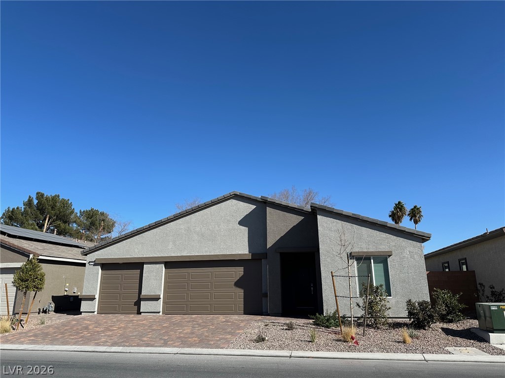 Modern gray single-story home with a two-car garage, paved driveway, and desert landscaping.