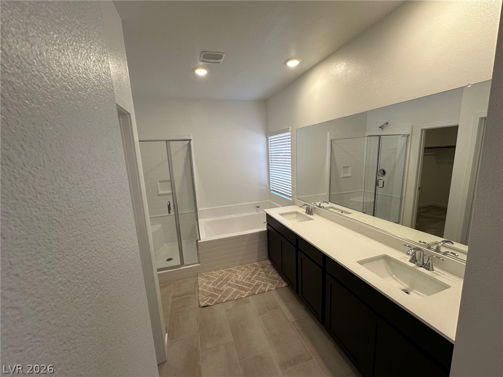 Bathroom with a double vanity, large mirror, bathtub, and glass-enclosed shower.
