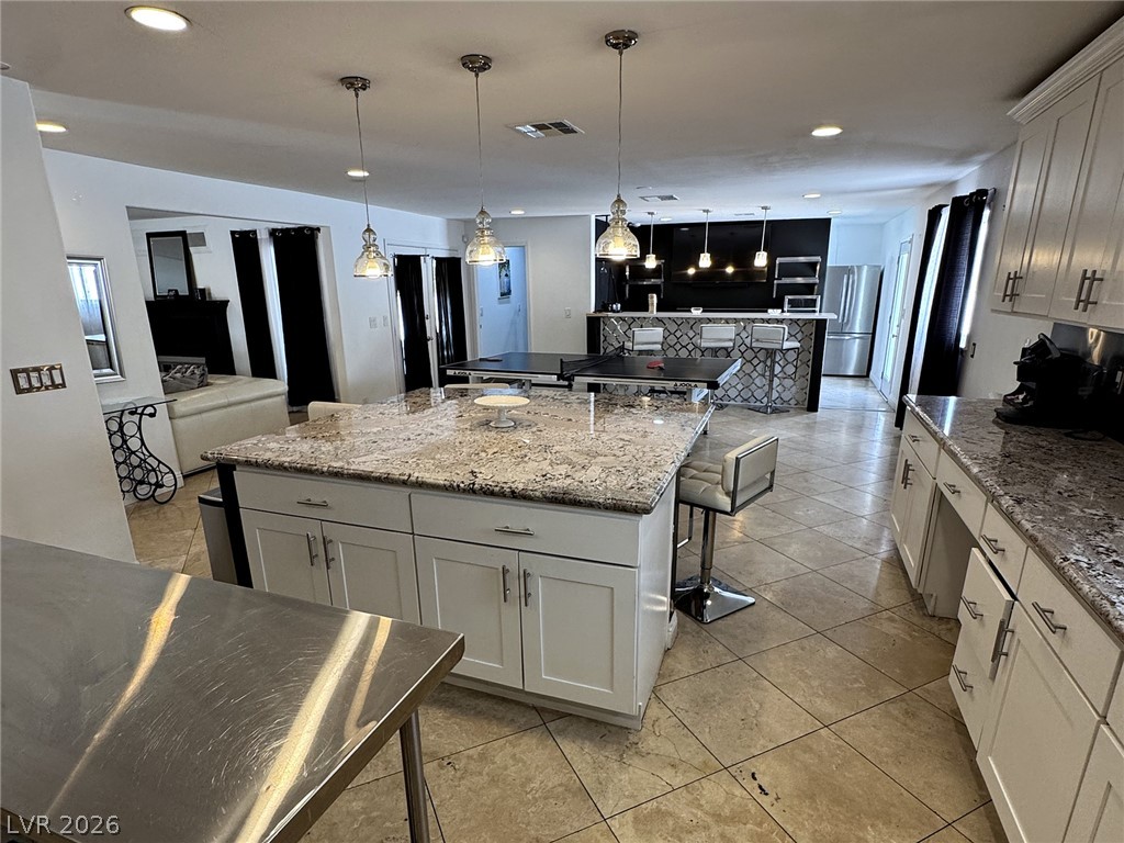 Open-plan kitchen with a granite island, pendant lights, and a breakfast bar with stools.