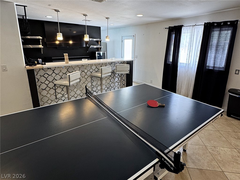 Game room with a ping-pong table and paddle, and a bar counter with three stools.