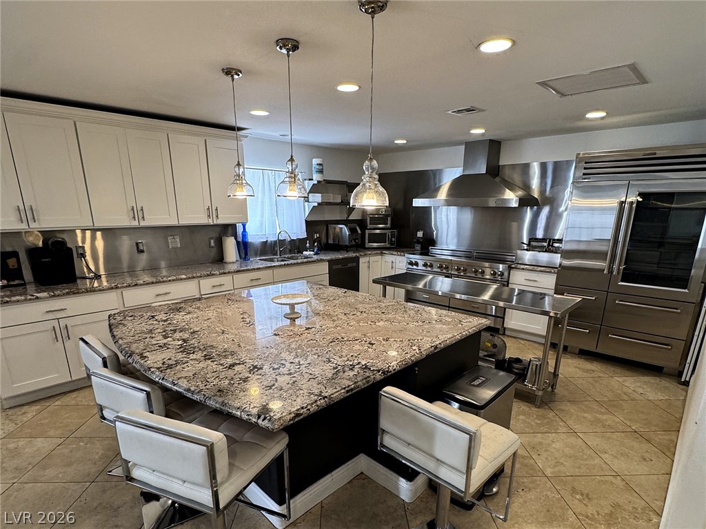 Kitchen with a large granite island, white cabinetry, and stainless steel appliances.