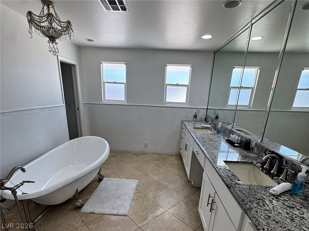 Bathroom with a clawfoot tub and granite double vanity beneath large mirrors.
