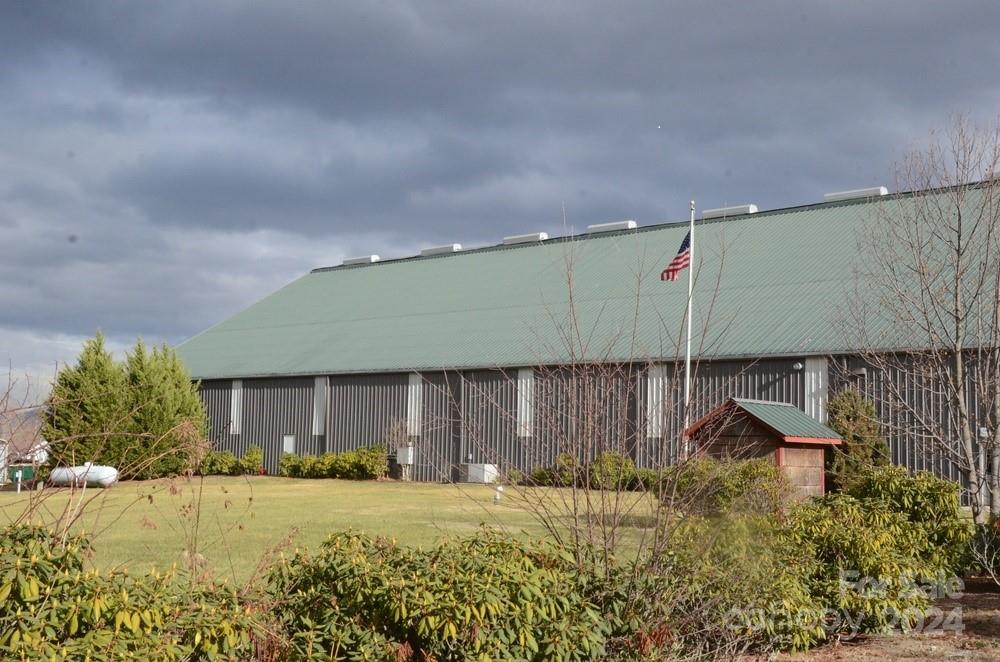 Large metal-sided building with a pale green roof and an American flag in front.