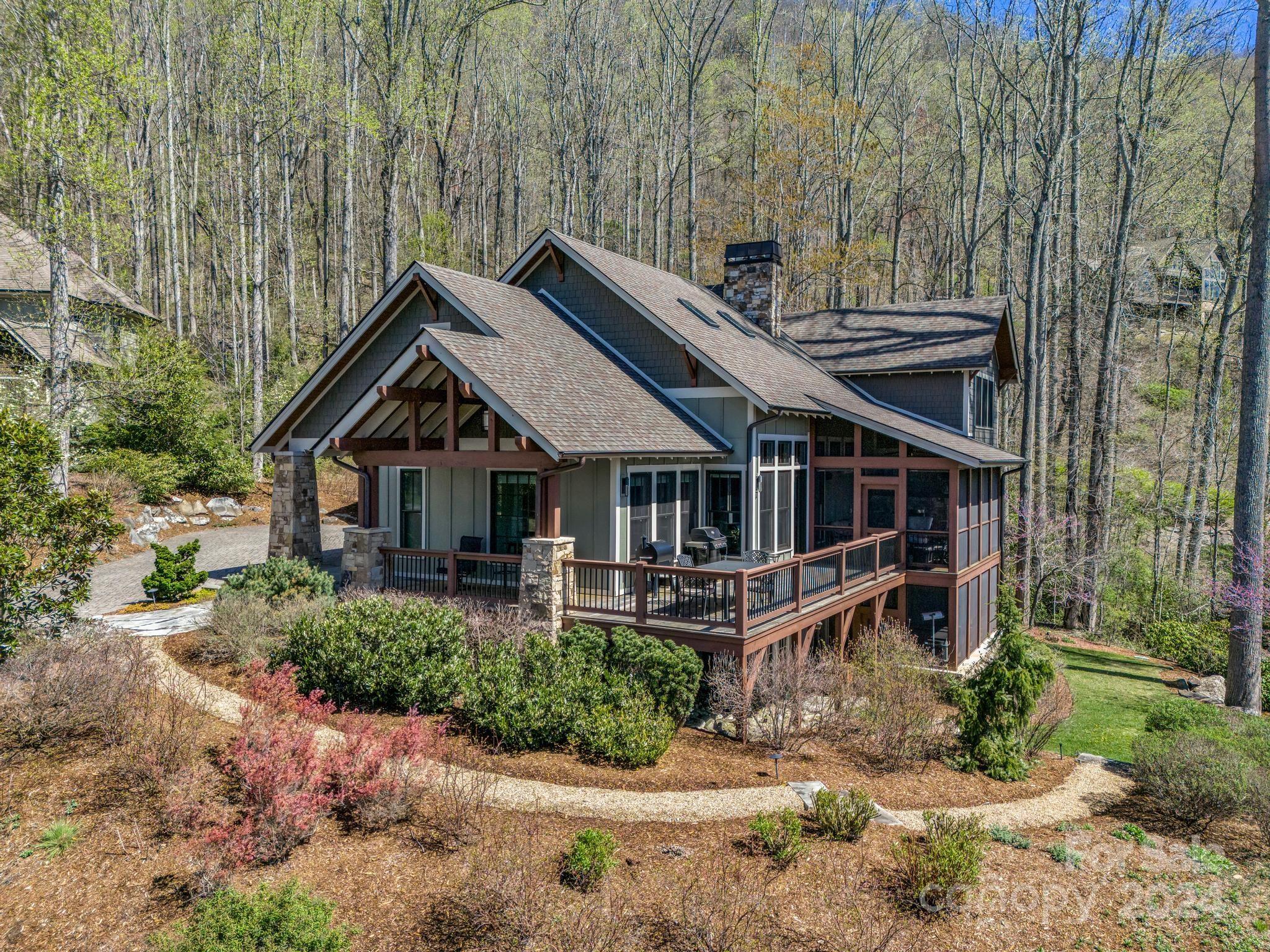 Wooded home with multiple gables, a stone chimney, and a broad elevated deck.