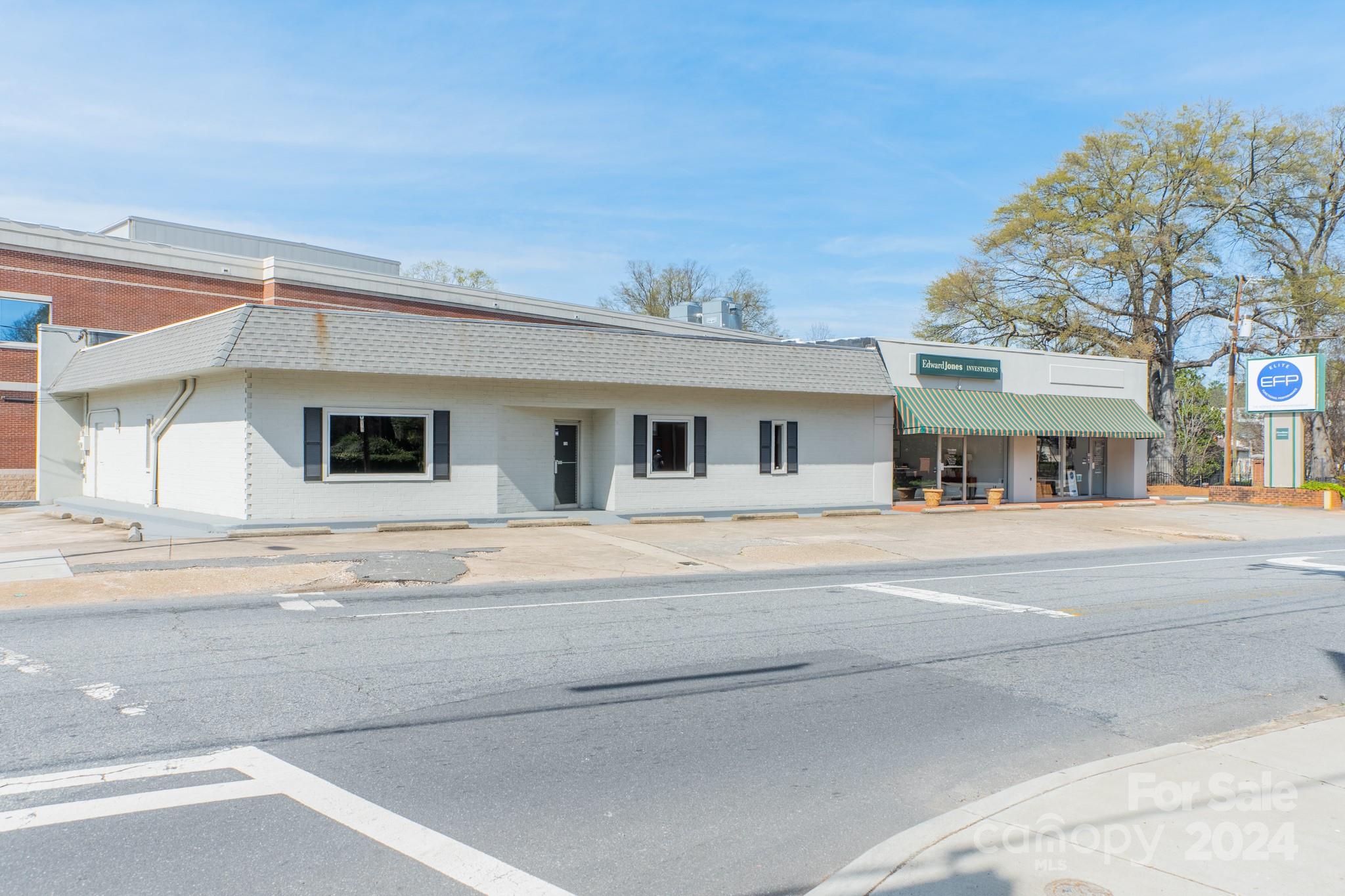 White commercial building beside an Edward Jones Investments storefront with a striped awning.