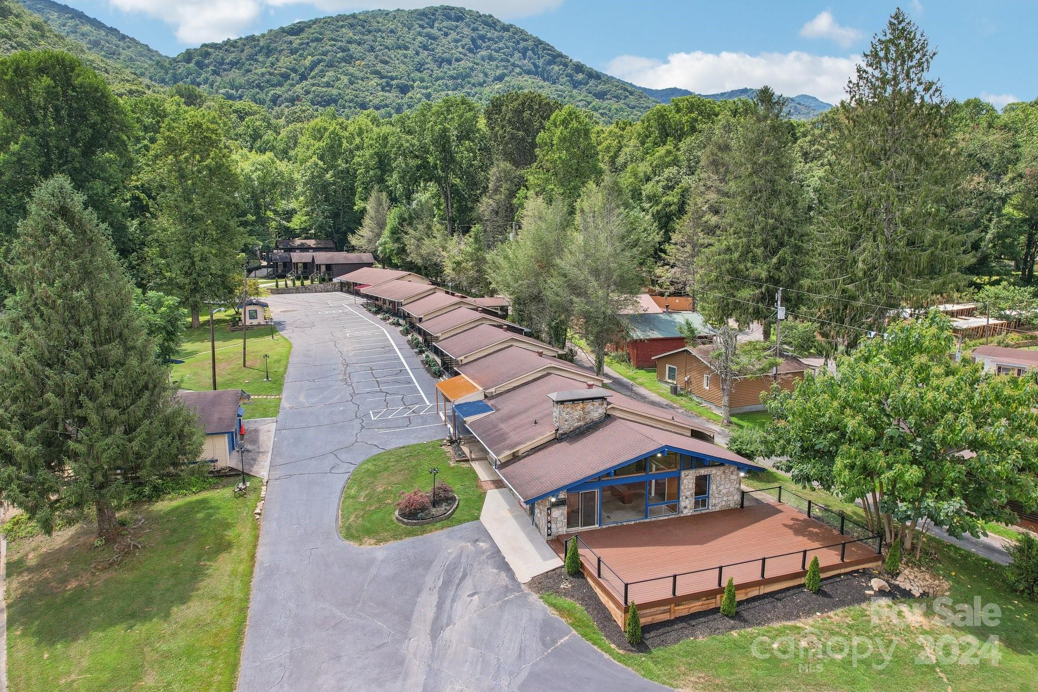 Aerial view of a mountain lodge complex with a row of cabins and a large deck.