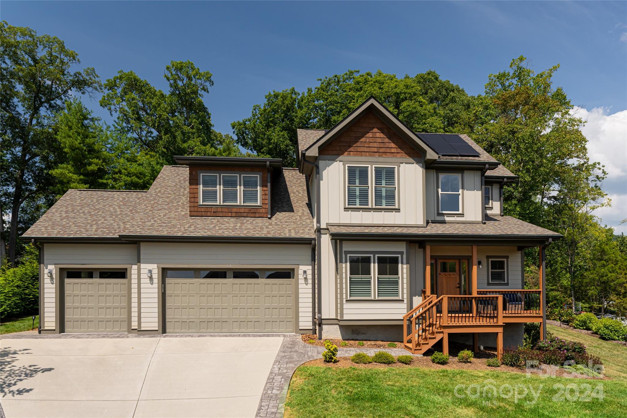 Two-story home with a two-car garage, wooden front porch, and solar panels on the roof.