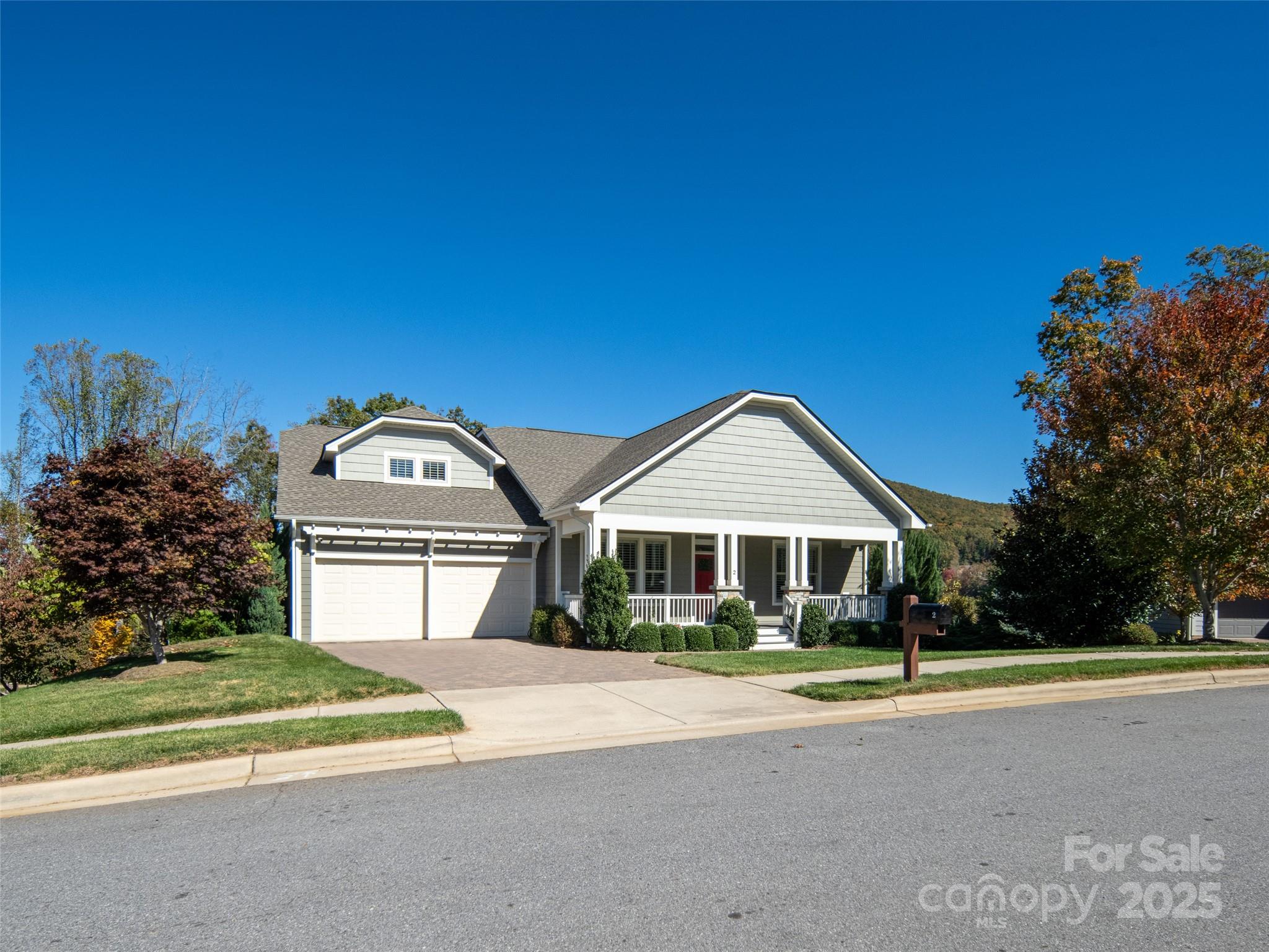 Gray house with a two-car garage and covered porch, framed by autumn trees.