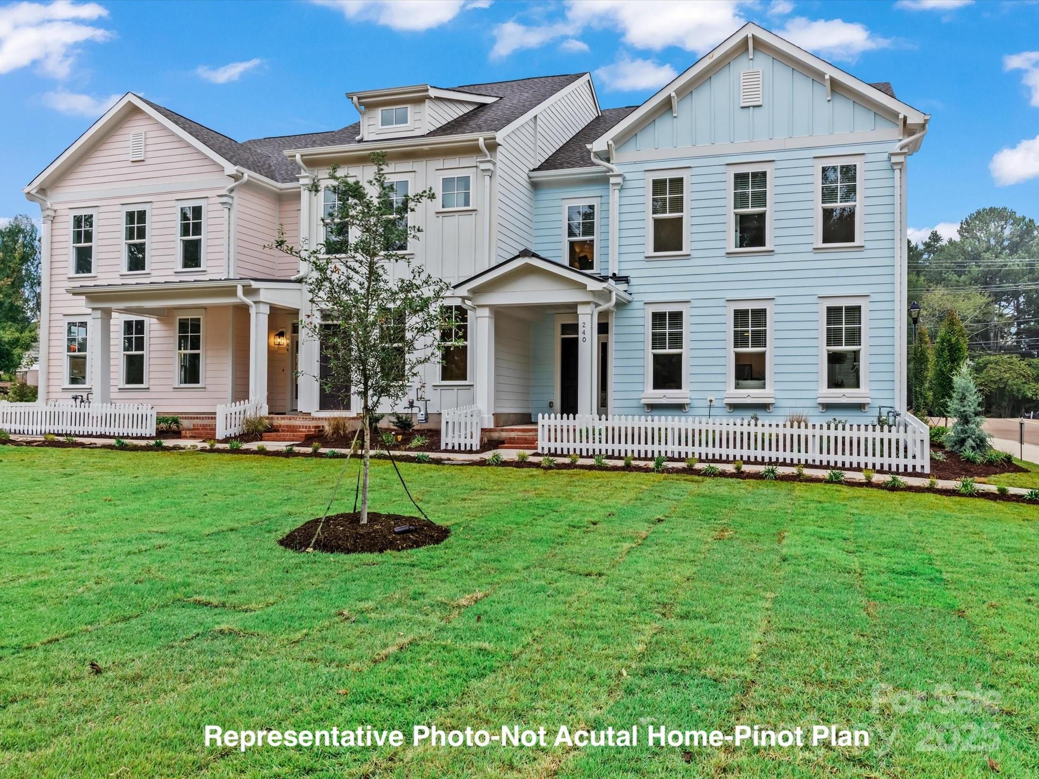 Pastel attached townhomes behind white picket fences, with a broad lawn and a representative-photo disclaimer.