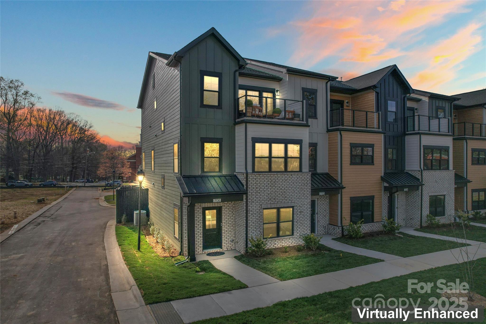Modern townhomes with balconies and brick accents beneath a colorful dusk sky.