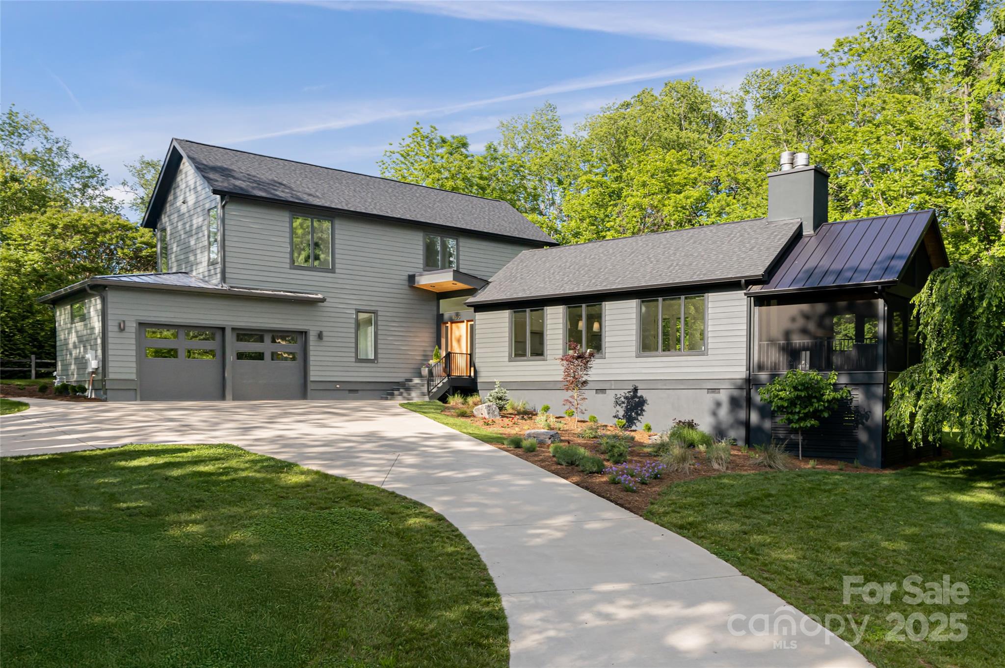Modern gray two-story house with an attached garage, landscaped yard, and screened porch.